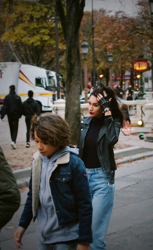 two people walk on the sidewalk with other pedestrians