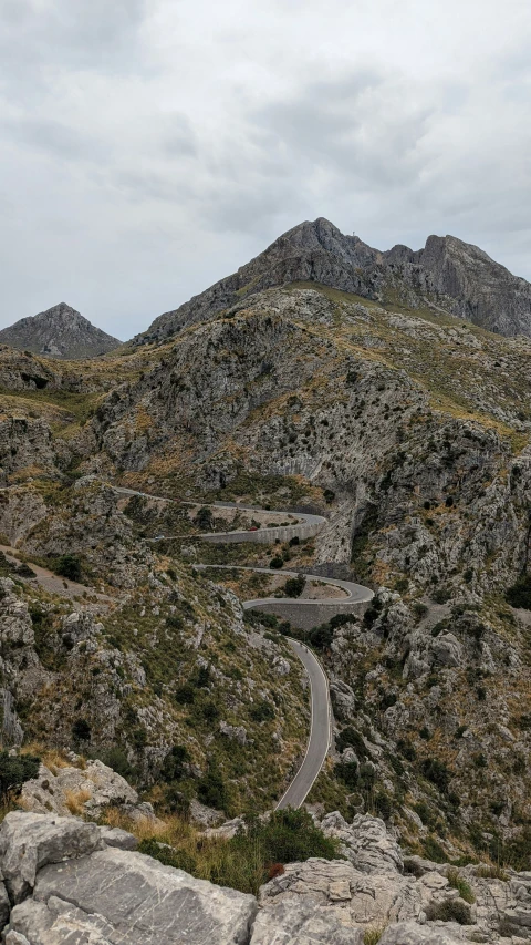 a curve in the road between rocks and grass