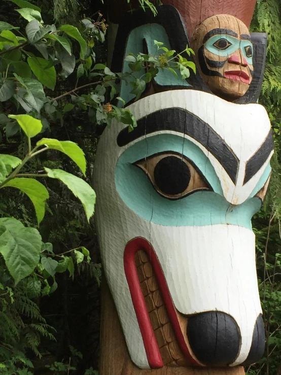 a large wooden carved totem sitting next to a bush