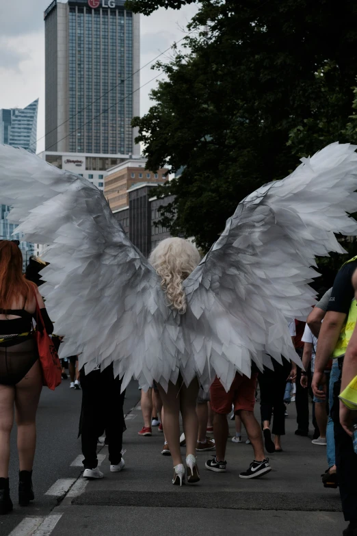 a woman in white and black wings walking down a street