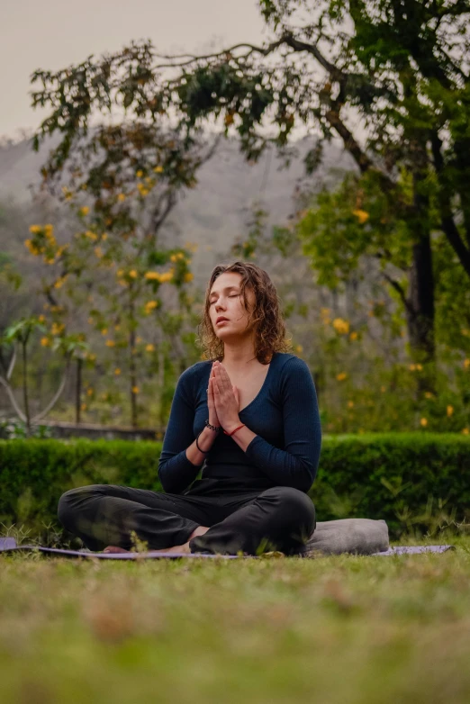 a woman sitting in yoga meditation position with her eyes closed