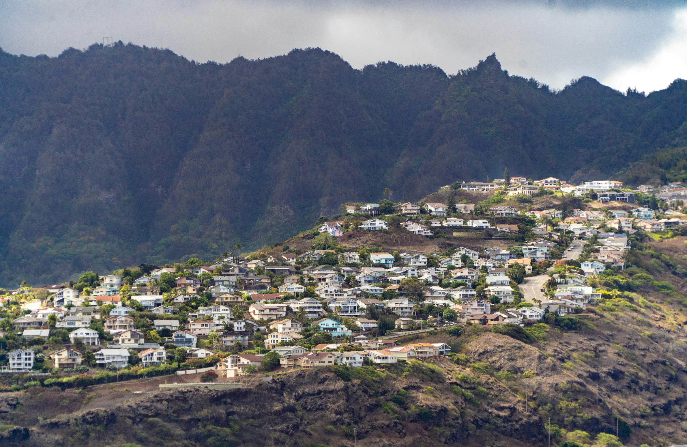 some houses sit on a mountain with mountains in the background