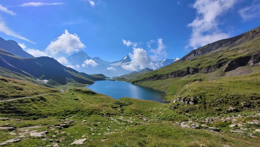 a lake surrounded by mountains and grass