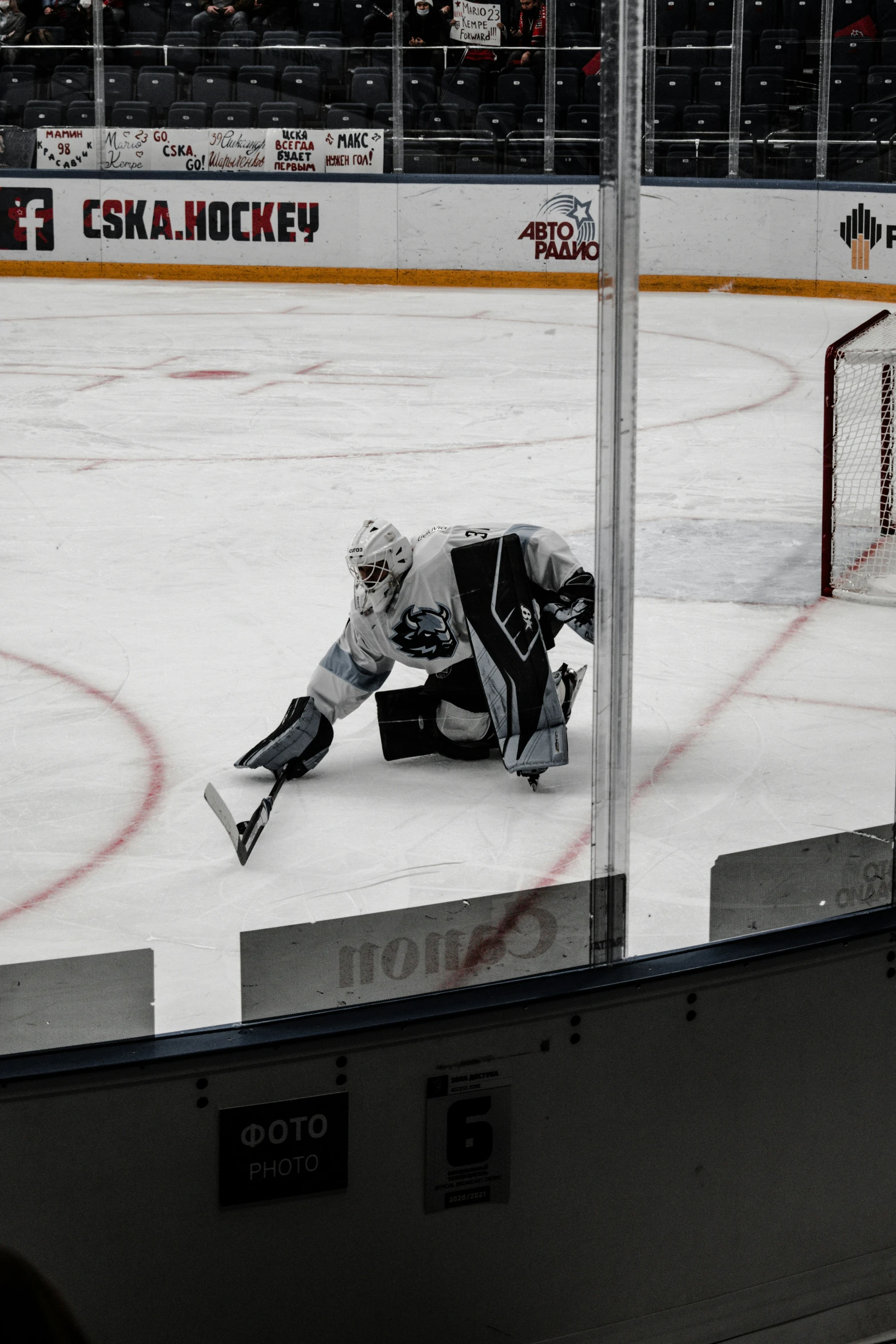 goalie crouches down to look at the puck as they watch as the crowd watches