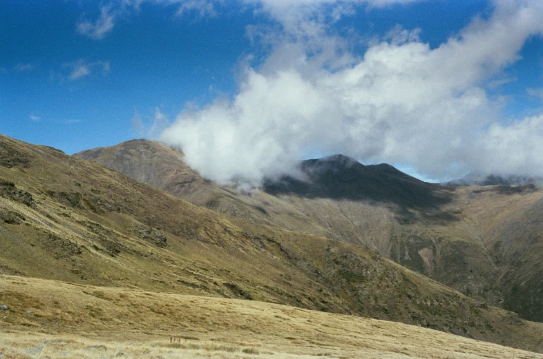 the mountains are covered in clouds and brown grass