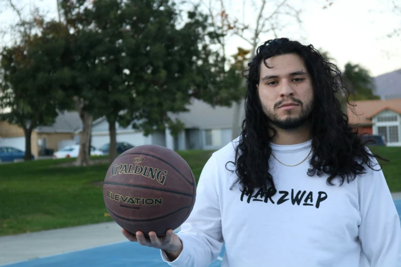 a man with long hair holding a basketball