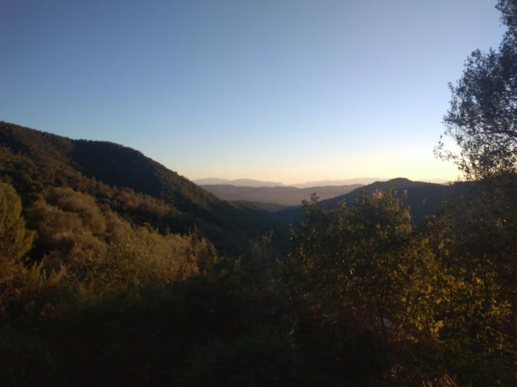 the sun shines brightly above a mountain valley