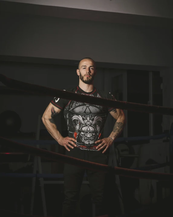 a man in shorts and a t - shirt stands next to a boxing ring