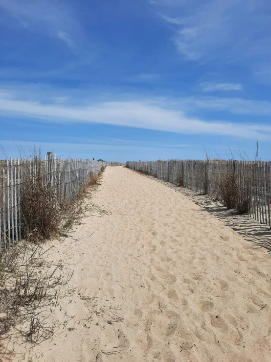 a beach road with some fencing in the sand