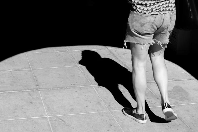 a woman is standing on a sidewalk looking down at her cell phone