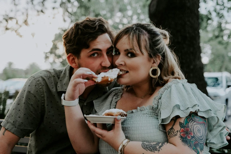 a woman eats food with her husband near a tree