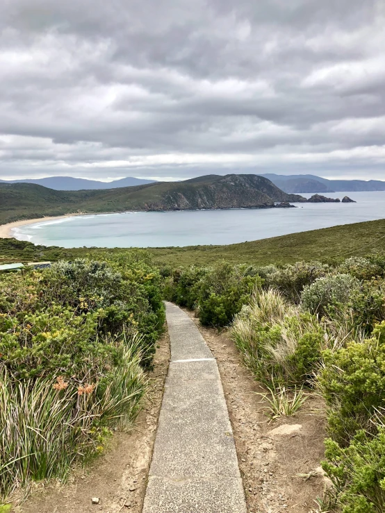 a gravel path leads down to the water on a cloudy day