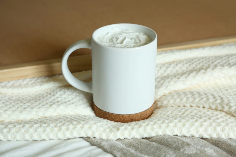 a cup filled with liquid sitting on a bed