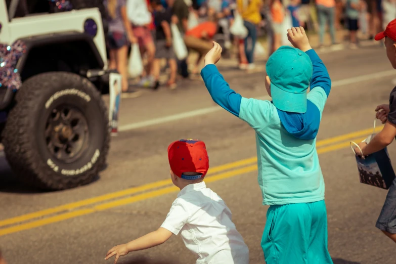 two children with hands raised walking down the street