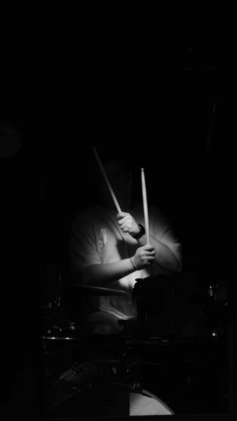 a man in black holding up two drums and drumming on stage