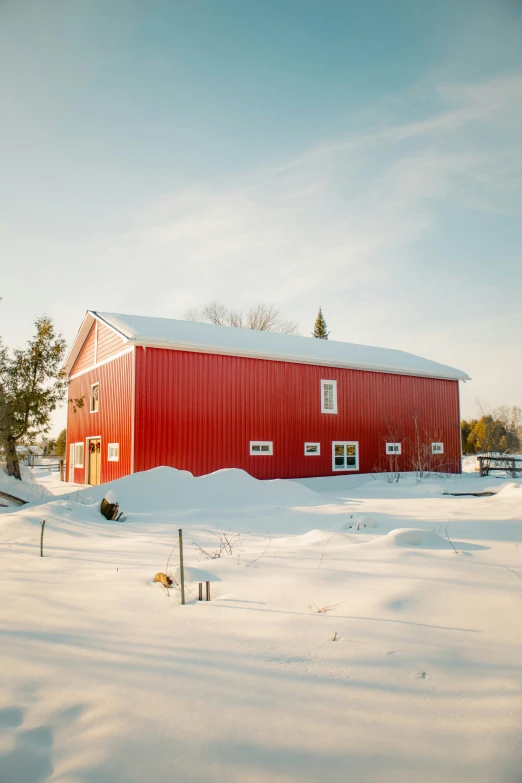 a large red barn surrounded by snow covered ground