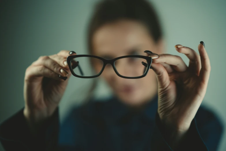 a woman with glasses on her face holding up the camera