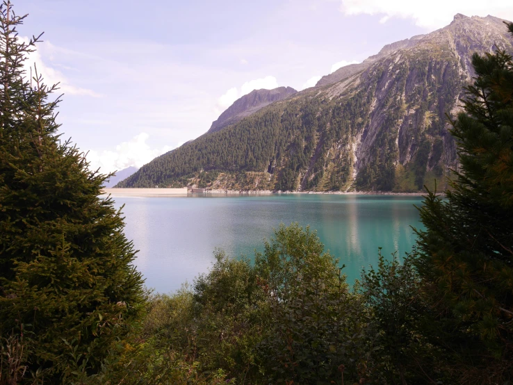 a large mountain overlooking a river with clear water