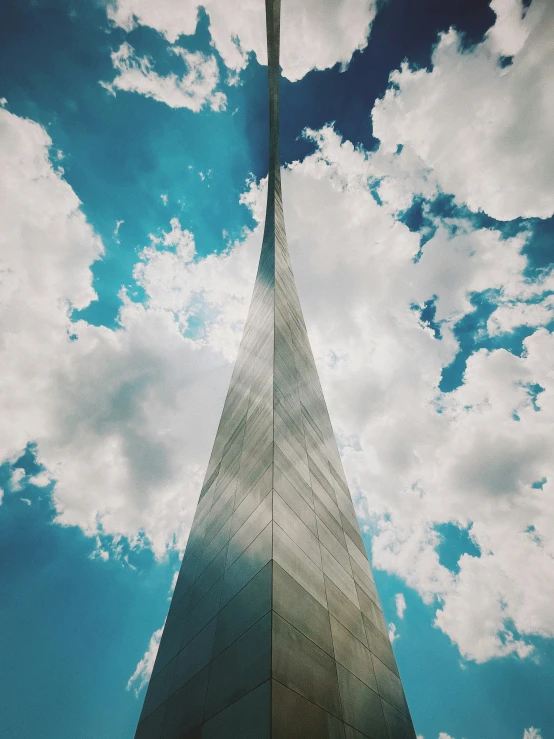 a tall gray spire sits under blue sky with clouds