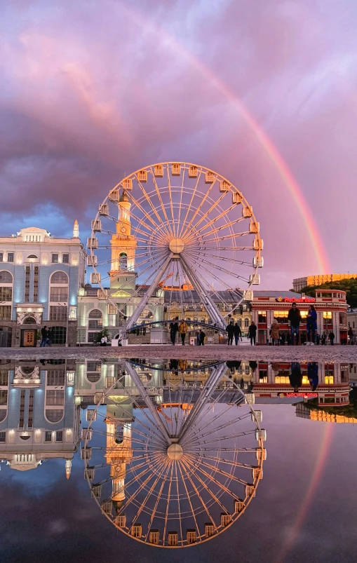 rainbow in the sky and a ferris wheel with buildings around