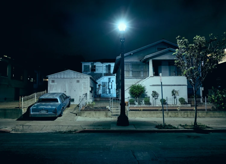 a street light stands in the dark over a row of houses