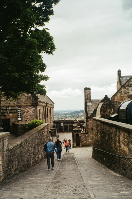 people walk down a cobble stone sidewalk in an old town