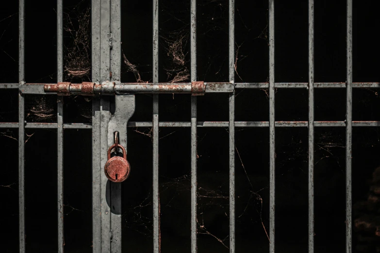 a rusty lock and iron bars in a dark cell