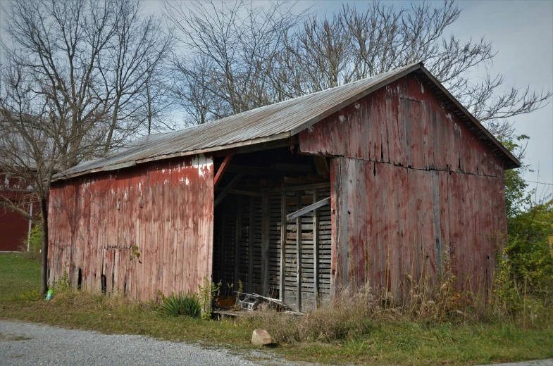 the side of a barn with a door and a rusty window