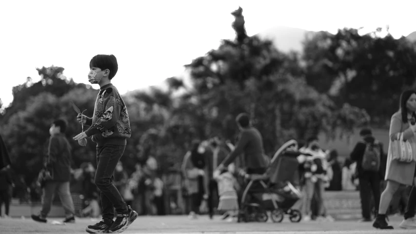 a child walking down the sidewalk with a lot of people in the background