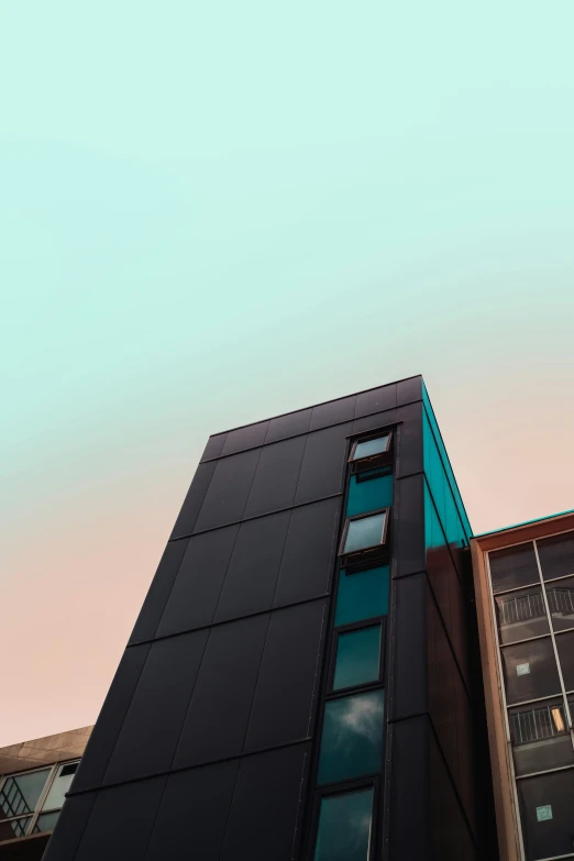 a very tall black building against a light blue sky