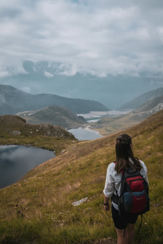 a girl is looking over a hill towards the water