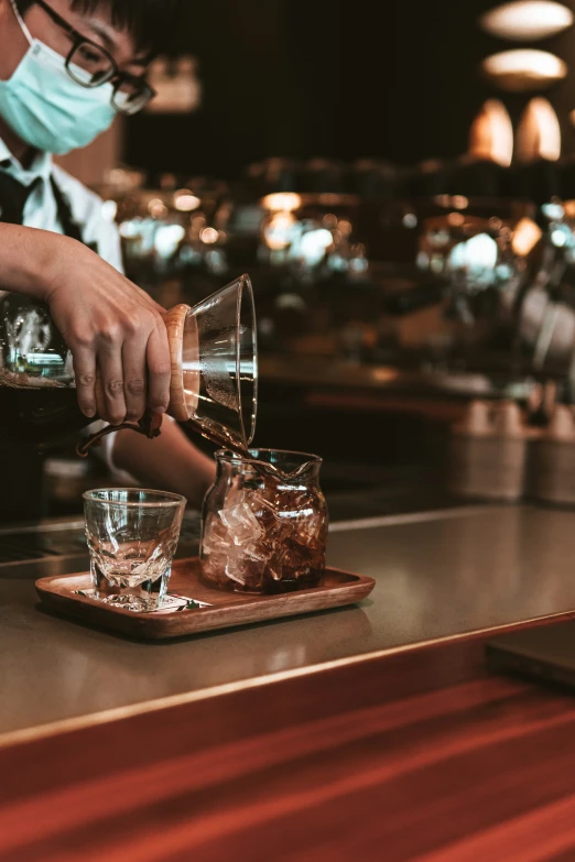 a bartender pours a beverage into glasses at a bar