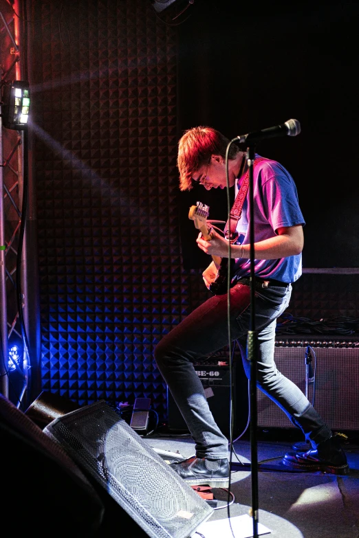 man standing on stage with microphone and cellphone in hand