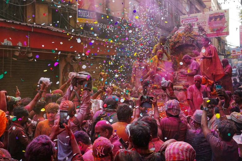 people in colorful costumes are throwing holi at the crowd