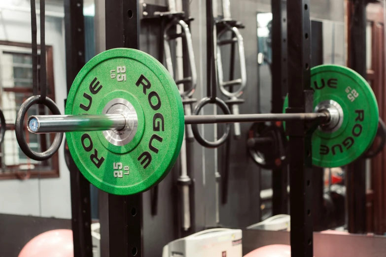 a close up of a green barbell near many other gym equipment