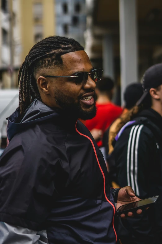 man with dreadlocks and sunglasses standing outside on sidewalk