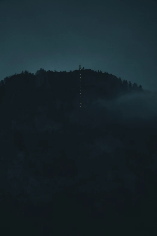 a very tall hill with fog and some trees