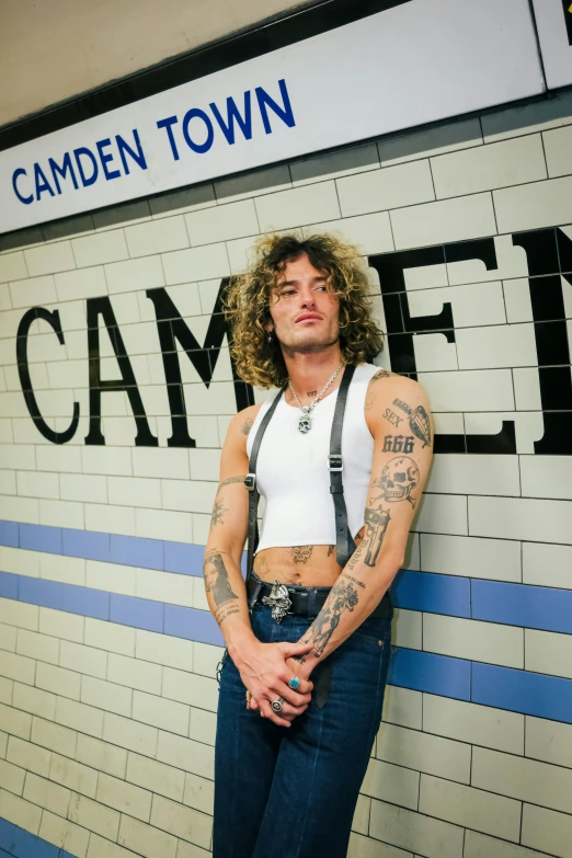 the woman with a tattoo stands next to the sign for camden