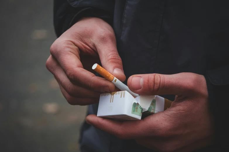 the man is holding two cigarettes in their hands