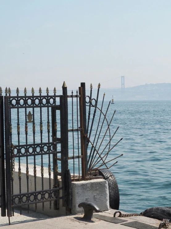 a metal fence next to the ocean on a beach