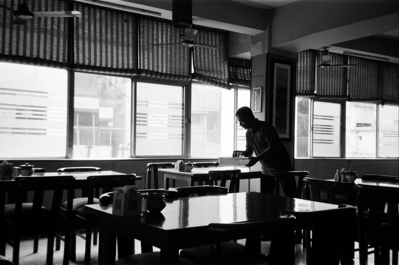 black and white image of person looking at tables in classroom