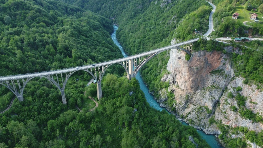 a river flows under a bridge spanning over a wide gorge