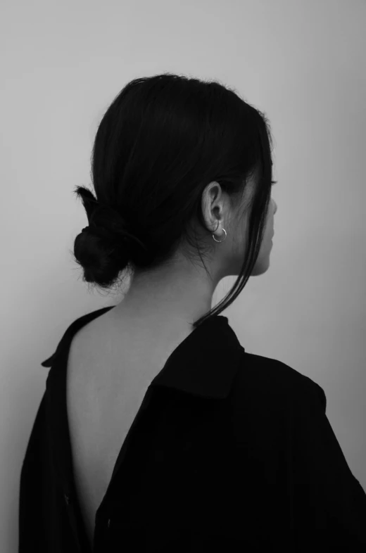 a woman standing in front of a white wall wearing earrings