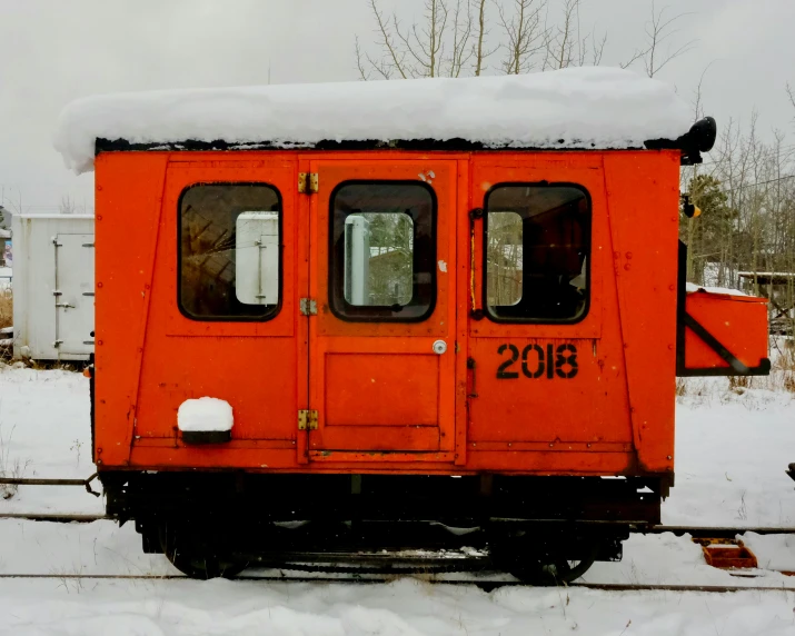 an orange train car is covered in snow