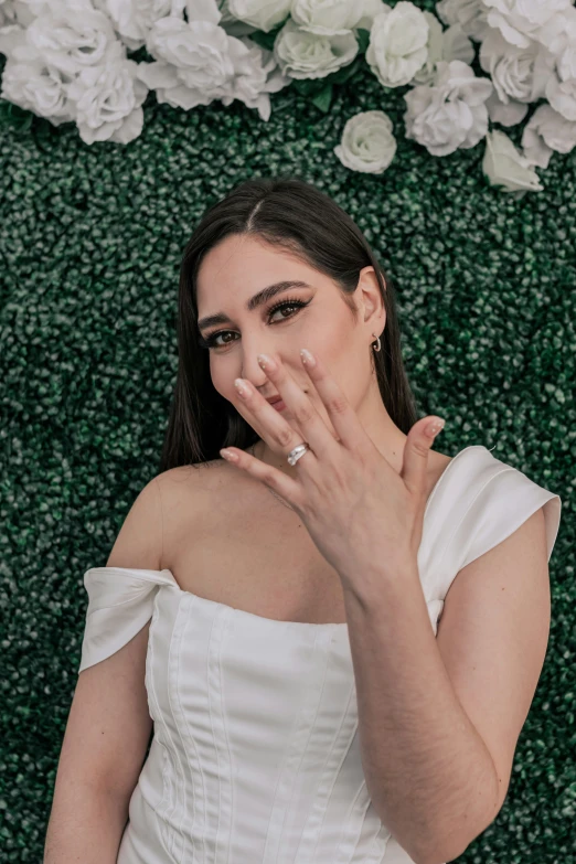 a woman posing in front of flowers wearing a white dress