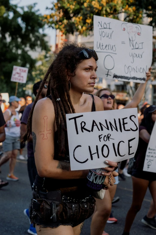 a man in a costume holds up signs with writing on them while others march through the street