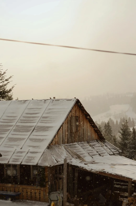 old barn in the middle of a snowstorm on a hill side