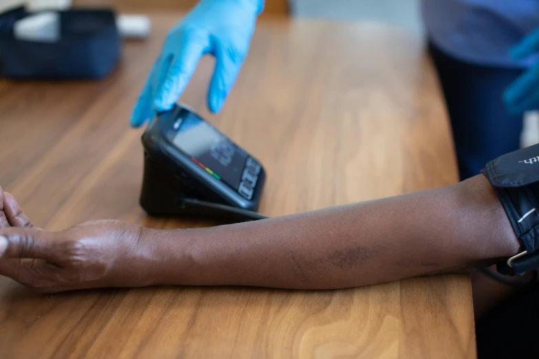 a woman holding onto a cell phone while another person uses a blue glove