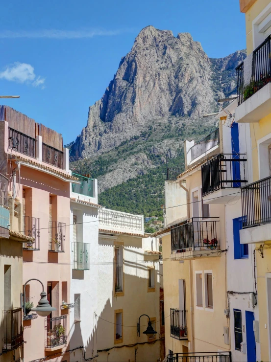 several buildings line the streets below mountains with balconies