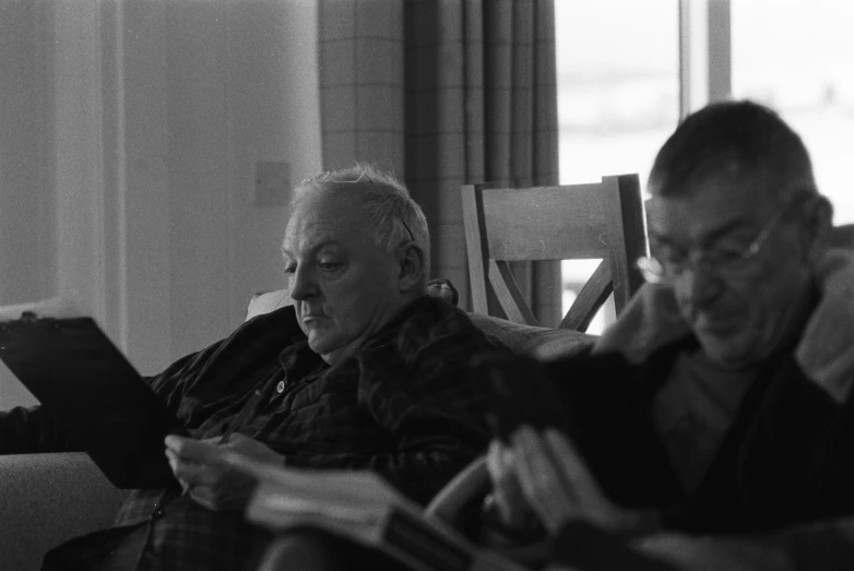 an older couple sitting on a couch in front of a window